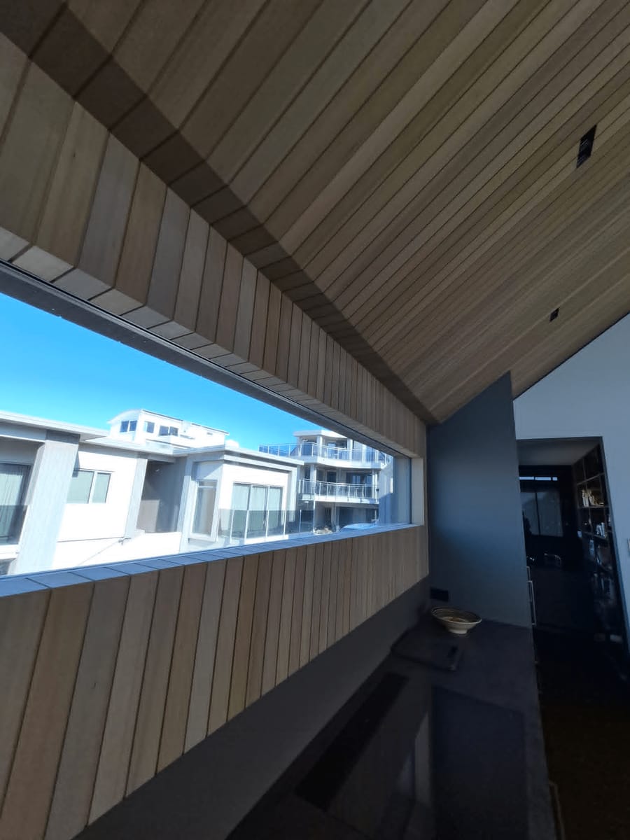 Timber-lined ceiling and wall with a long horizontal window in a completed new build