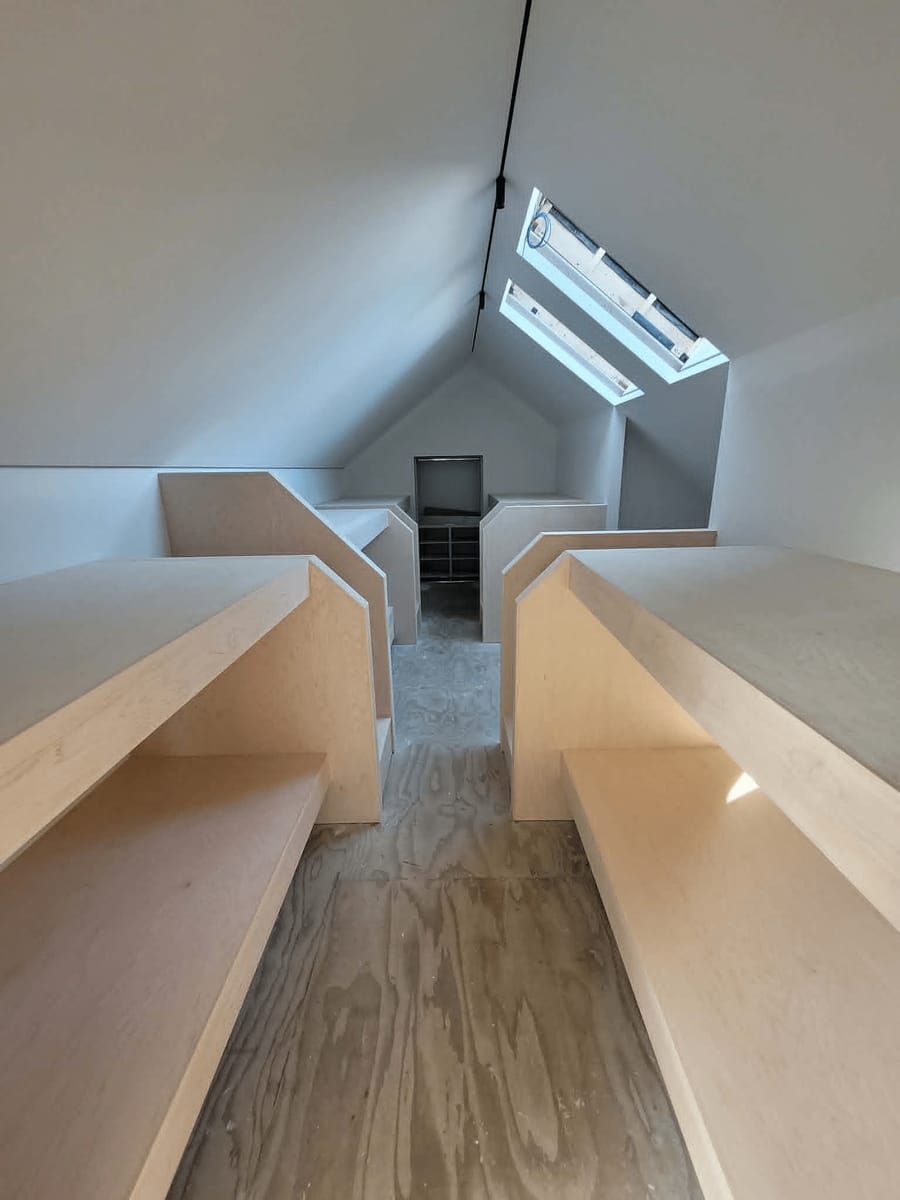 Built-in plywood bunks and storage in a loft under a gabled roof with skylights